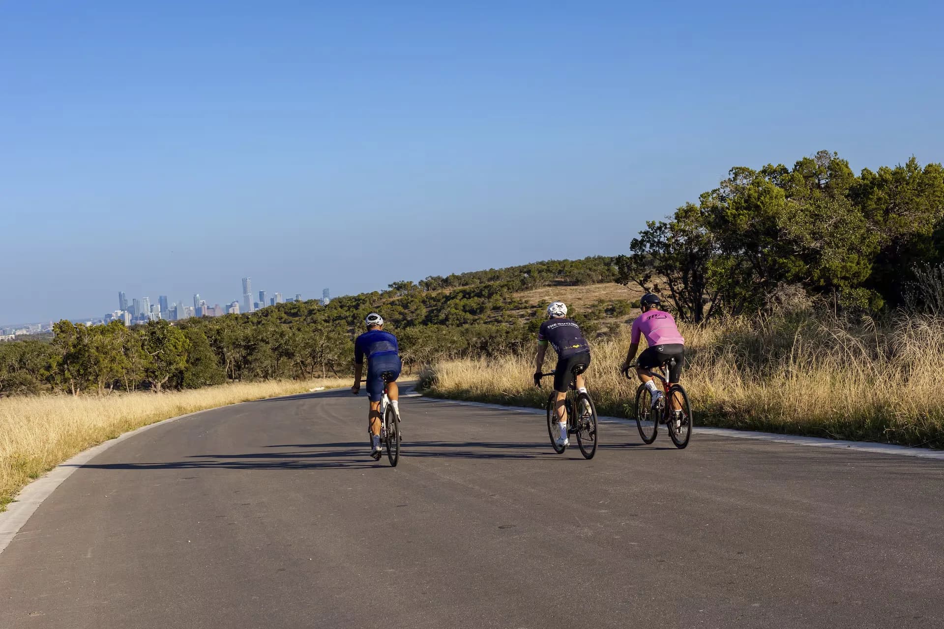 Three riders rolling toward the Austin skyline